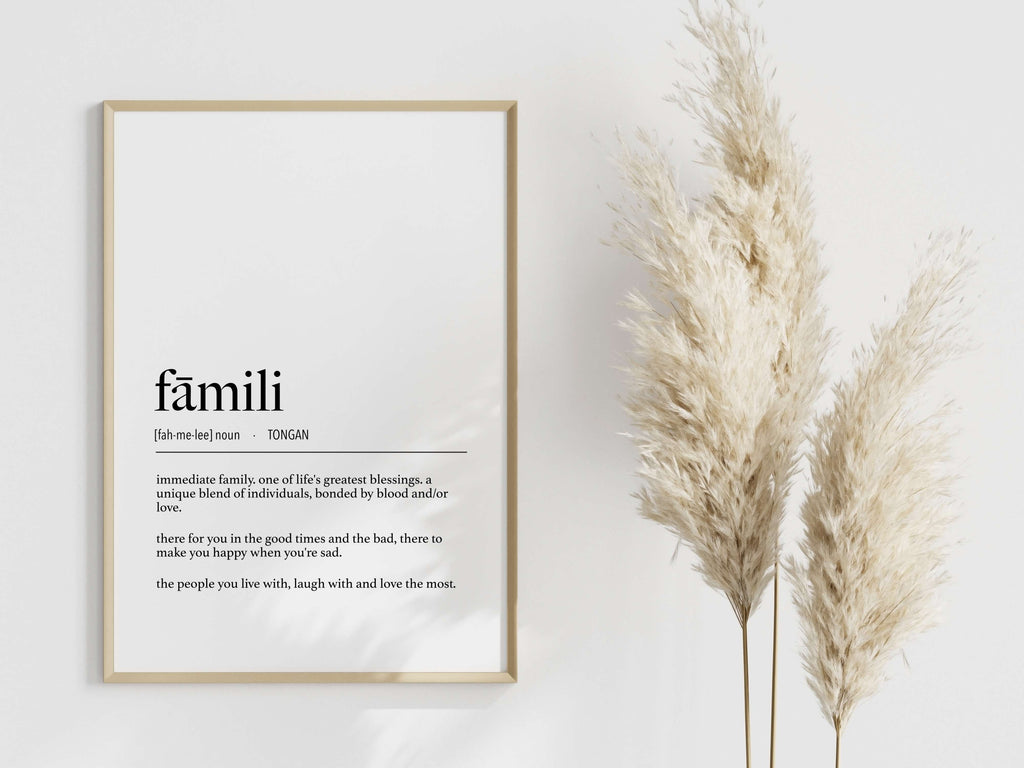 Framed print with the word 'famili' and its definition on a white wall with decorative plants.